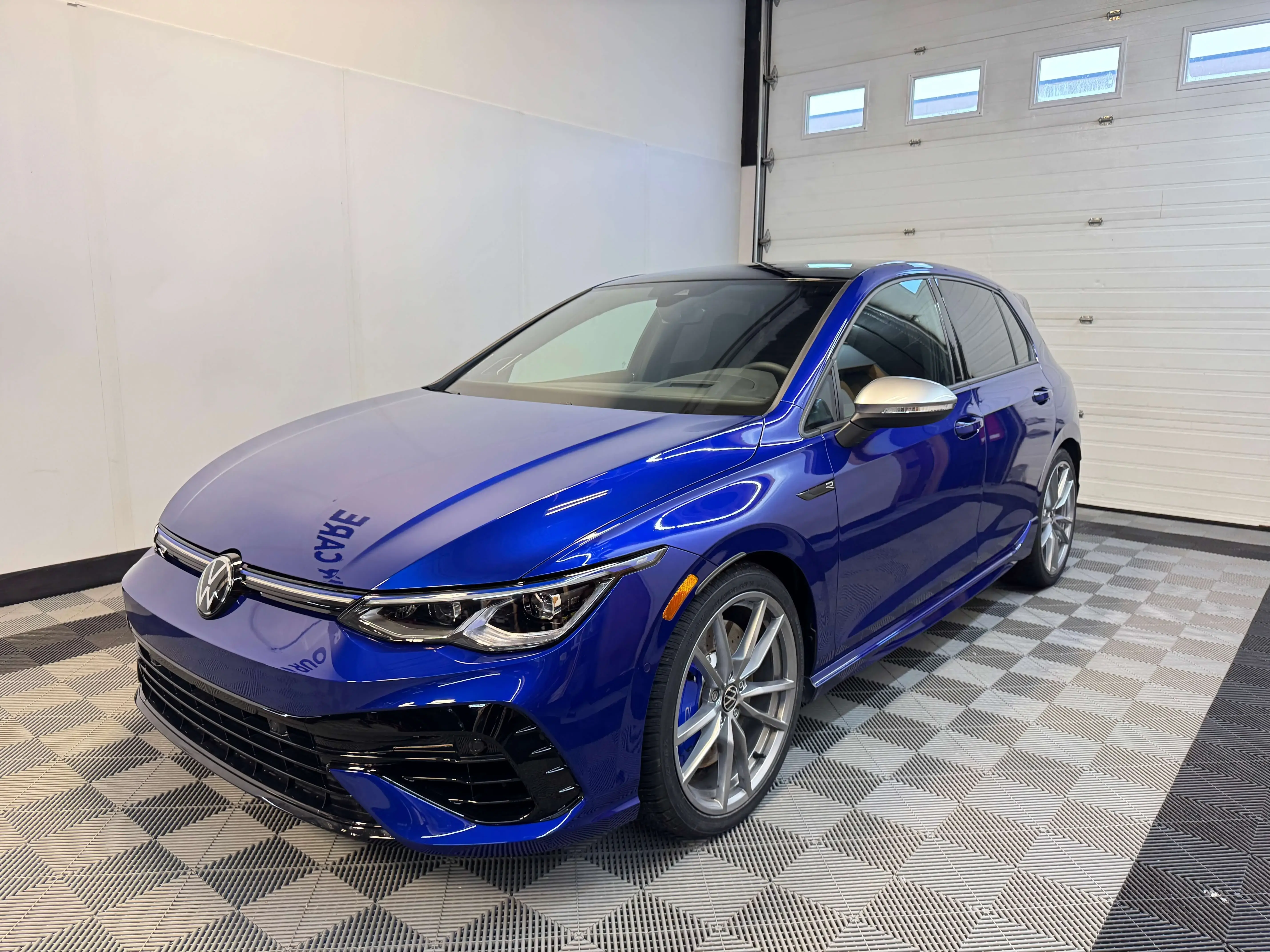 Detail Lab. Low-angle shot of a green Ford Bronco showcasing its rugged off-road tires and black grille. The Bronco logo is prominently displayed on the front.