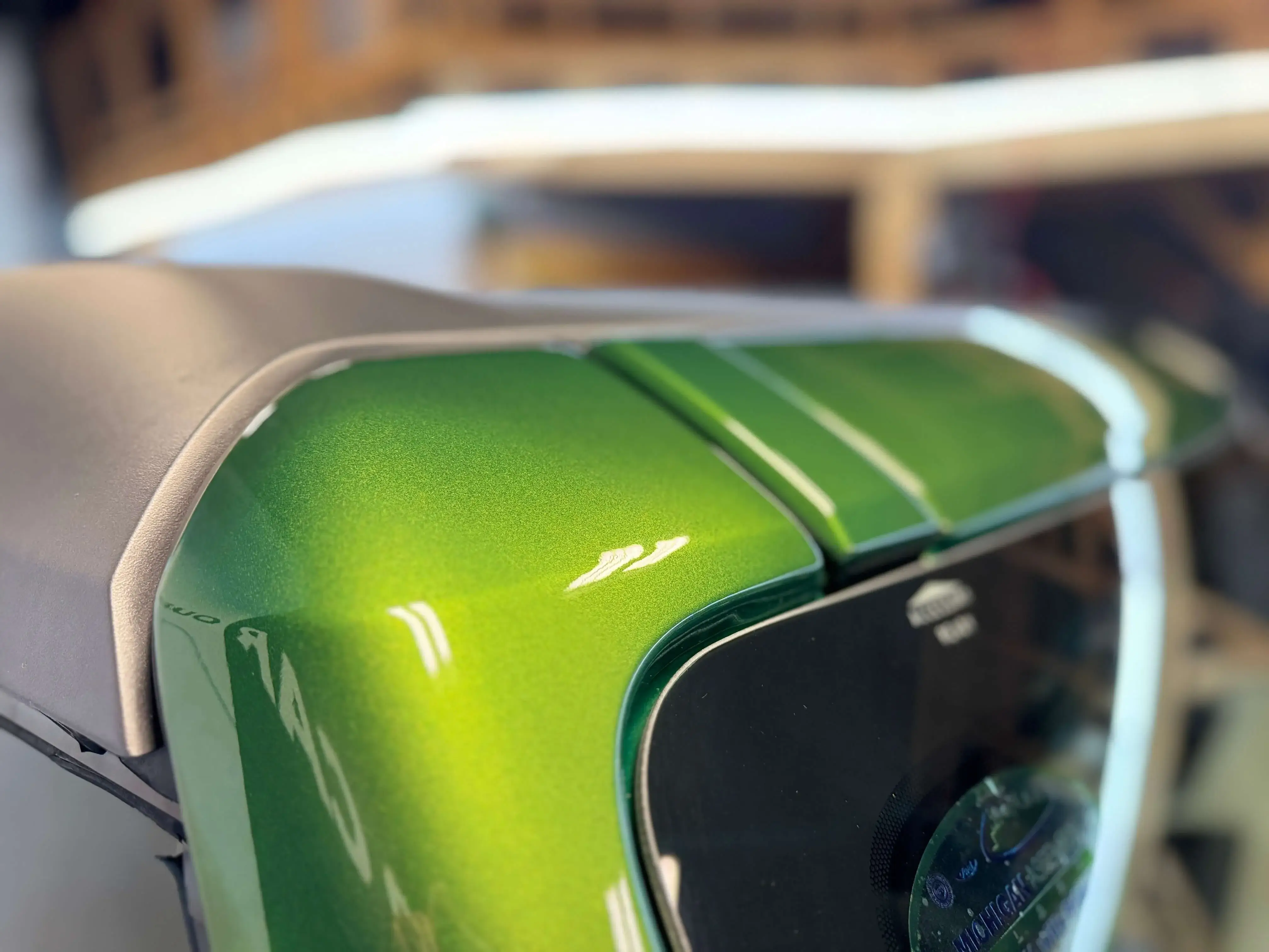 Detail Lab. Close-up of the hood of a blue Volkswagen Golf R with a high-gloss finish. The reflections of the detailing shop’s lighting and branding are visible.